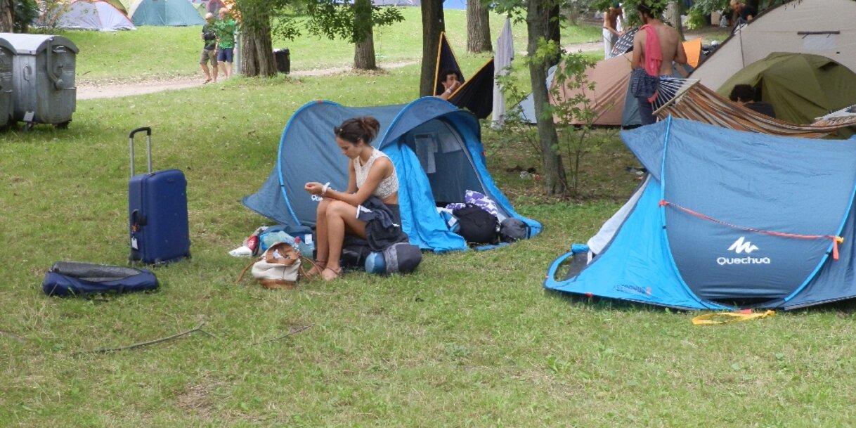 A célba érkezés pillanatai: „A gyakorlott fesztiválozó igyekszik gyorsan túlesni, túllendülni a formaságokon… Az elsőbálozó pedig még ezeket is élvezi! Úgymint karszalag, bejutás, ideálisnak