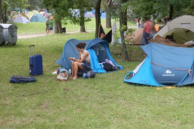 A célba érkezés pillanatai: „A gyakorlott fesztiválozó igyekszik gyorsan túlesni, túllendülni a formaságokon… Az elsőbálozó pedig még ezeket is élvezi! Úgymint karszalag, bejutás, ideálisnak